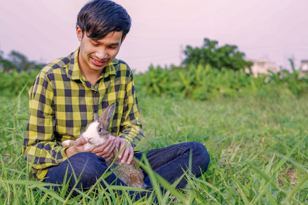 farmer taking care of a young cute rabbit in the field,focus at rabbitの写真素材