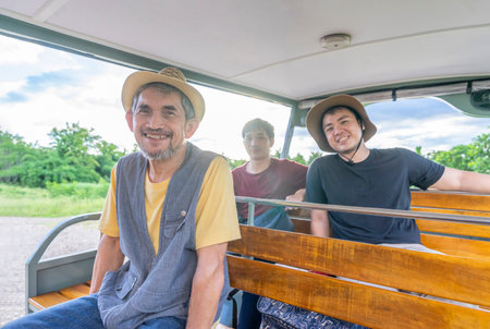 tourists looking at the camera while sitting on a tourist cart and enjoying nature at a...