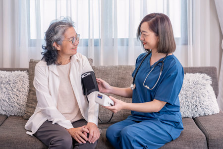 A nurse visiting  senior woman at home,taking vital signs,blood pressure,notify the result and giving advice,elderly health care,home care servicesの写真素材