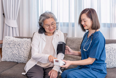 A nurse visiting  senior woman at home,taking vital signs,blood pressure,notify the result and giving advice,elderly health care,home care servicesの写真素材