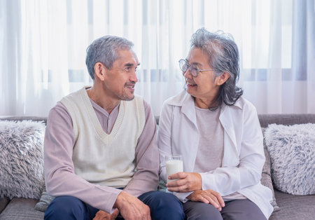 romantic asian senior couple enjoy having healthy drink together in the living room,elderly healthy lifestyle,relaxation,domestic lifeの写真素材