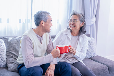 romantic asian senior couple enjoy having healthy drink together in the living room,elderly healthy lifestyle,relaxation,domestic lifeの写真素材