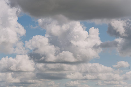 A mix of fluffy white clouds and grey storm clouds on a blue sky background