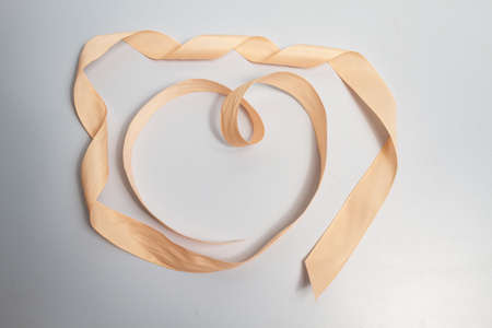 Heart with decorative ribbon on a gray background.の写真素材