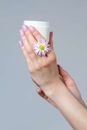 Well-groomed women's hands with a jar of cream.の写真素材