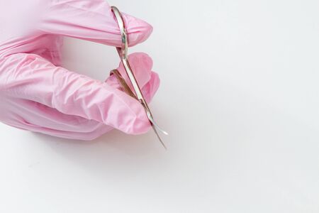 The hand in the pink sterile glove is held by the manicure scissors.の写真素材
