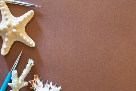 Brown background with a starfish and art brushes.