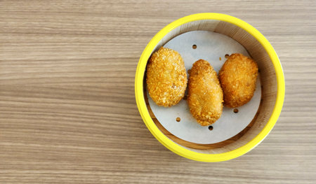 Three pieces of cheese shrimp dim sum (one of the popular snacks in Indonesia) in a minimalist round wooden container on the table.の写真素材