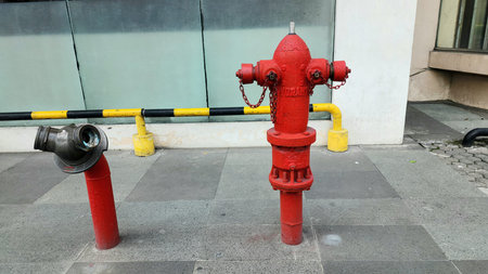 A red fire hydrant, made of iron, is installed in front of a shopping center.
