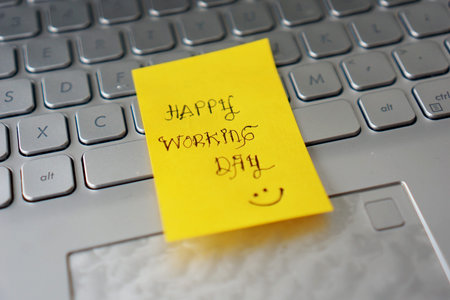 Happy working day on orange sticky paper (Sticky Notes), stuck on a laptop keyboard
