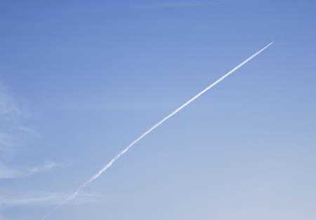 airplane leaving jet-steam track on a clear blue sky の写真素材