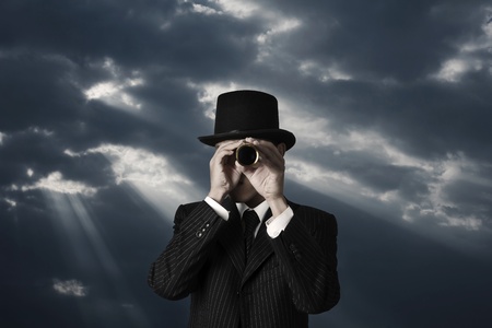 business man looks through a telescope in darkness の写真素材
