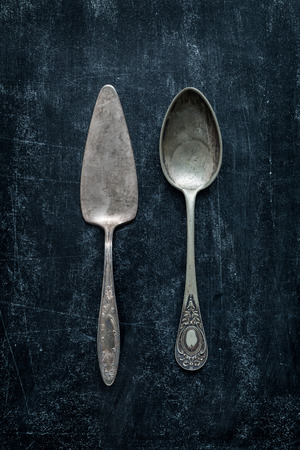 Old vintage silverware (cutlery) on black chalkboard background from above (top view).の写真素材