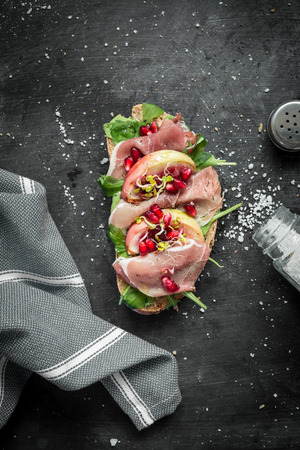 Italian prosciutto sandwich captured from above (top view). Black chalkboard as background. Flat lay composition with free text space.の写真素材