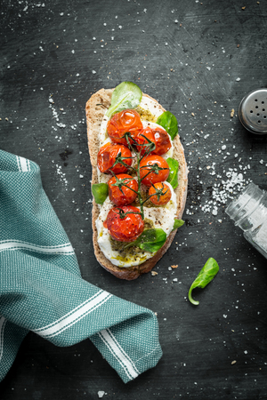 Italian mozzarella and roasted cherry tomatoes sandwich captured from above (top view). Black chalkboard as background. Flat lay composition with free text space.の写真素材