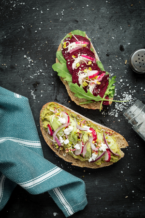 Vegetarian (beetroot, avocado, goat cheese, radish) sandwiches captured from above (top view). Black chalkboard as background. Flat lay composition with free text space.の写真素材