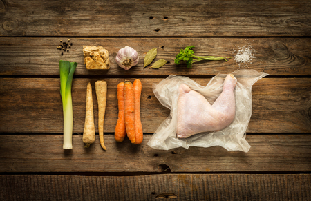 Cooking - chicken stock (bouillon, soup) recipe ingredients on rustic wooden background. Poultry and root vegetables -  rural kitchen scenery captured from above (top view, flat lay).の写真素材