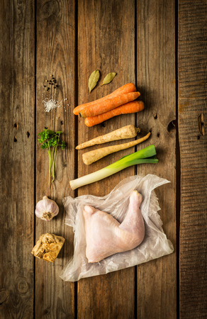 Cooking - chicken stock (bouillon, soup) recipe ingredients on rustic wooden background. Poultry and root vegetables -  rural kitchen scenery captured from above (top view, flat lay).の写真素材
