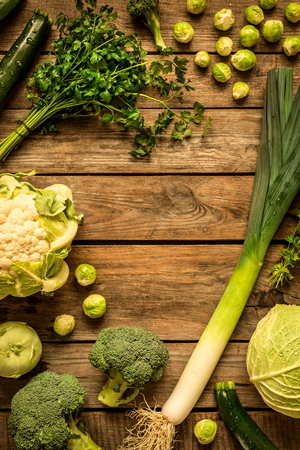 Green vegetables on vintage rustic wooden background. Rural kitchen table - flat lay composition (from above, top view). Layout with free text space.の写真素材
