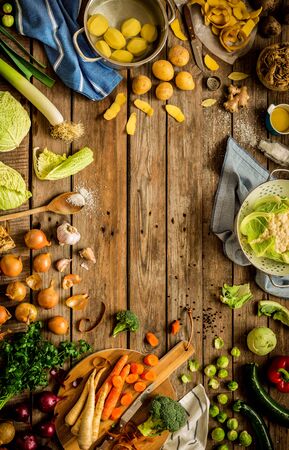 Cooking scene - preparing autumn (fall) vegetables on vintage rustic wooden background. Rural kitchen table - flat lay composition (from above, top view). Layout with free text space.の写真素材