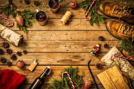 Winter christmas weekend in country cottage (cabin) concept. Boots, hat, hot drinks, candy canes and firewood. Rustic layout, from above (flat lay). Vintage wooden background, free text (copy) space.の写真素材