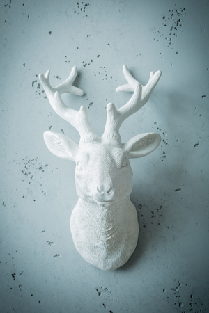 White deer head with antlers - decor or sculpture. Interior decoration on grey wall. Background layout with free text (copy) space.の写真素材