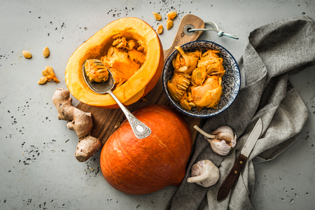 Kitchen - preparing pumpkin (squash) for cooking. Moody rustic still life captured from above (top view, flat lay). Grey stone background.の写真素材