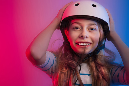 Portrait of happy smiling young caucasian child girl in skate helmet - safety, sports and active lifestyle concept. Colorful background, layout with free text (copy) space.の写真素材