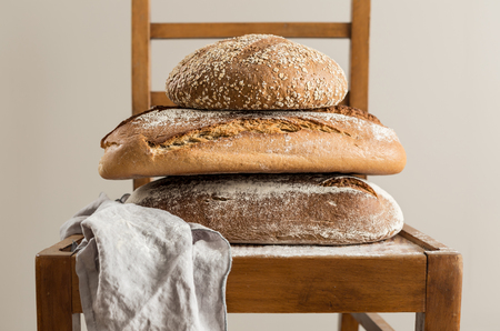 Bakery - pile of rustic crusty loaves of bread on vintage chair - still life. Small business and slow food concept.の写真素材