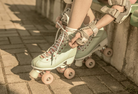 Skater girl putting on mint retro roller skates outdoor - hobby, sports and active lifestyle...