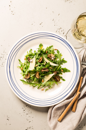 Salad with black truffles, arugula (rucola), parmesan cheese and sunflower seeds. Plate captured from above (top view, flat lay). Grey stone background. Layout with free text space.の写真素材