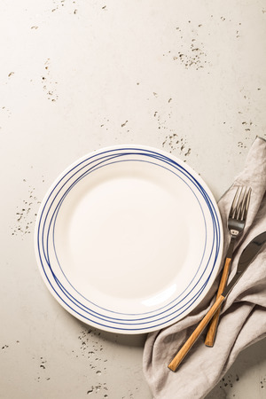 Empty white plate, napkin and cutlery on grey stone background. Composition captured from above (top view, flat lay), layout with free text (copy) space.の写真素材