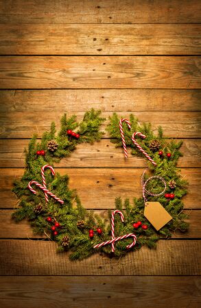 Christmas wreath made of natural green pine branches and decorations. Wooden background with free copy (text) space. Rustic composition captured from above (top view, flat lay).の写真素材