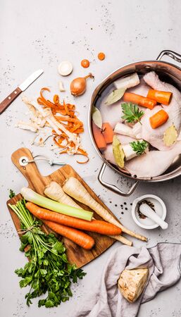 Cooking - preparing chicken stock (broth or bouillon) with vegetables in a pot. Kitchen - grey concrete worktop scenery from above (top view, flat lay).の写真素材