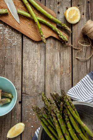 Asparagus in rural kitchen - preparing to cook on vintage wooden table. Rustic still life from above. Background layout with free text space.の写真素材