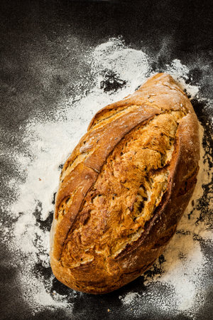 Rustic loaf of bread and flour on black chalkboard from above. Background layout with free text...