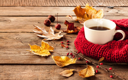 Hot coffee and autumn leaves on vintage wood background - seasonal relax conceptの写真素材