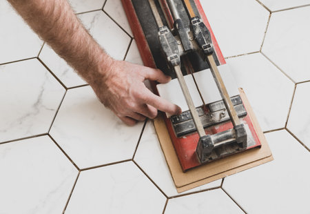 Interior finishing worker (tiler or handyman) using manual tile cutter. Bathroom renovation works.の写真素材