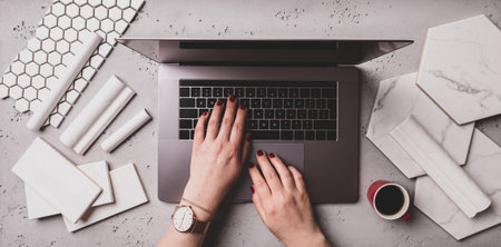 Interior design office. White and marble ceramic tiles, laptop computer and designer hands. Working...