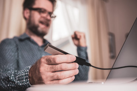 Successful caucasian man (businessman, investor) using laptop computer and cryptocurrency cold...