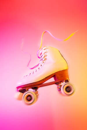 Classic white leather roller skate levitating on the vivid pink and orange background. Sports equipment and recreation. Dynamic pop art poster layout with free copy (text) space.の写真素材