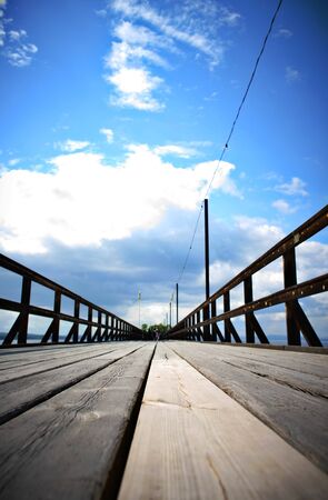 Old wooden pier at a lake with blue sky backgroundの写真素材