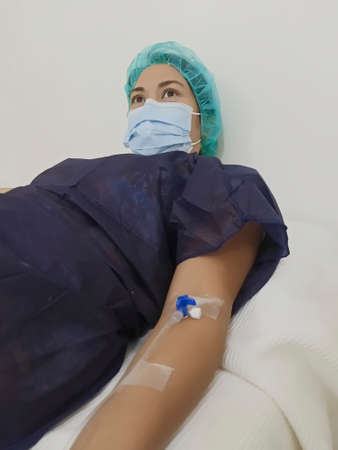 Young patient wearing face mask in hospital bed recovering from diseaseの写真素材