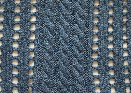 Knitted fabric texture. Blue color. Knitting on the knitting needles. Combined openwork knitting.