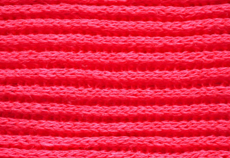 Knitted fabric texture. Red color. English knitting with front and back loops. Knitting on the...