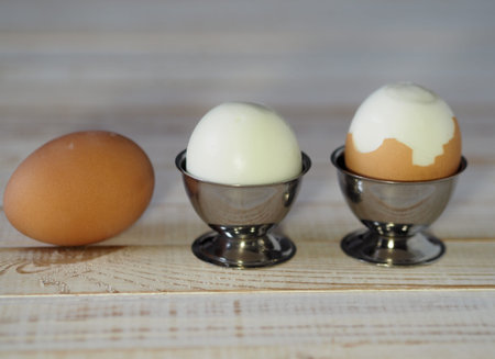 Chicken eggs on a wooden rustic white table. Purified and unpeeled. Shells. Preparing a filling for...