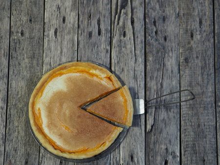 Round homemade pie with pumpkin, chopped walnuts, dipped in beaten eggs with sugar. Wooden rustic...