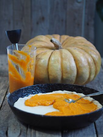 Round homemade pie with pumpkin. Stage of cooking. We spread the filling. Wooden rustic background.の写真素材