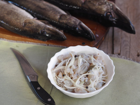 salad of freshly salted pike river fish on the background of pike river fish on a cutting board in...