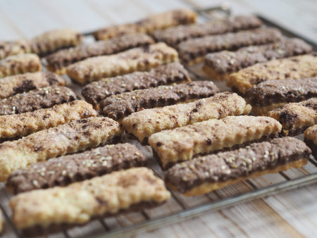 Homemade shortbread puff pastry chocolate cookies on a wooden background. On a metal grate for...
